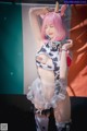 A woman with pink hair wearing a cow costume.