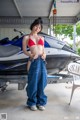 A woman in a red bikini standing next to a jet ski.