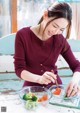 A woman sitting at a table with a bowl of vegetables.