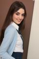 A woman in a school uniform leaning against a wall.