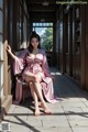 A woman in a pink robe sitting on a chair.