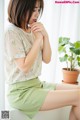 a woman sitting on a window sill next to a potted plant