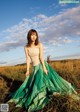 A woman in a long green skirt standing in a field.