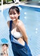 A woman in overalls standing next to a swimming pool.