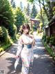 A woman in a kimono walking down a path in a park.