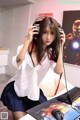 A woman sitting at a desk with a computer and headphones on.