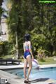 A woman in a bathing suit standing next to a swimming pool.