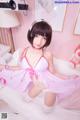 A woman in a pink lingerie sitting on a bed.
