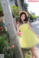 A woman in a yellow dress and straw hat posing for a picture.