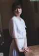 A woman in a white dress standing next to a table.