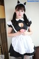 A woman dressed as a maid holding an apple.