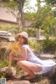 A woman in a straw hat sitting on a rock.