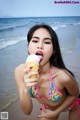 A woman in a bikini eating an ice cream cone.