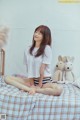 A woman sitting on a bed with a teddy bear.