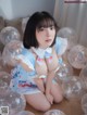 A woman sitting on the floor surrounded by balloons.