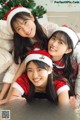 A group of three young women in santa hats posing for a picture.