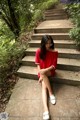 A woman in a red dress sitting on some steps.