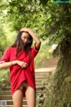 A woman in a red shirt is posing for the camera.