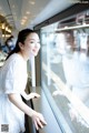 A woman in a white dress looking out of a window.