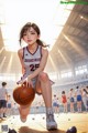 A woman holding a basketball on top of a basketball court.