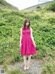 A woman in a pink dress standing in a field.