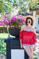 A woman in a red top and straw hat posing for a picture.