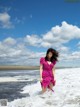 A woman in a pink dress standing in the ocean.