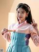 A woman in a blue and pink hanbok holding a ruler.