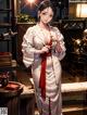 A woman in a white kimono standing in a room.